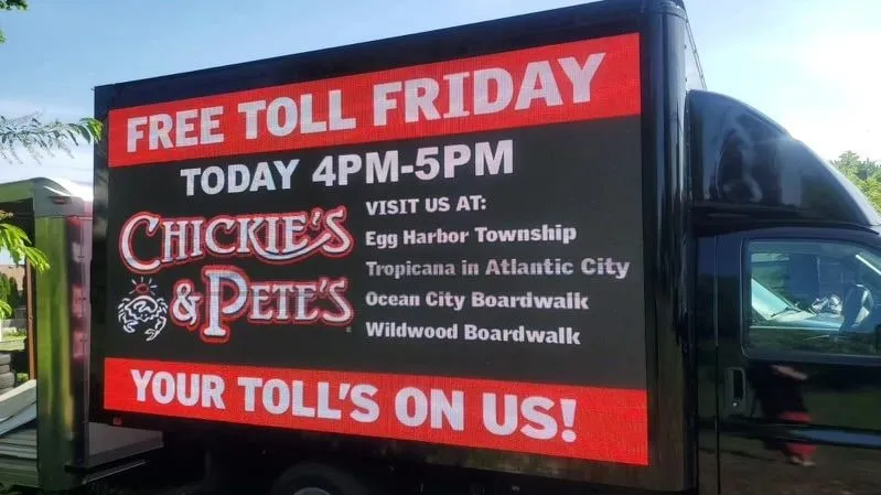A Brandwagon LED truck screen running a Chickie’s & Pete’s Free Toll Friday ad listing its shore locations